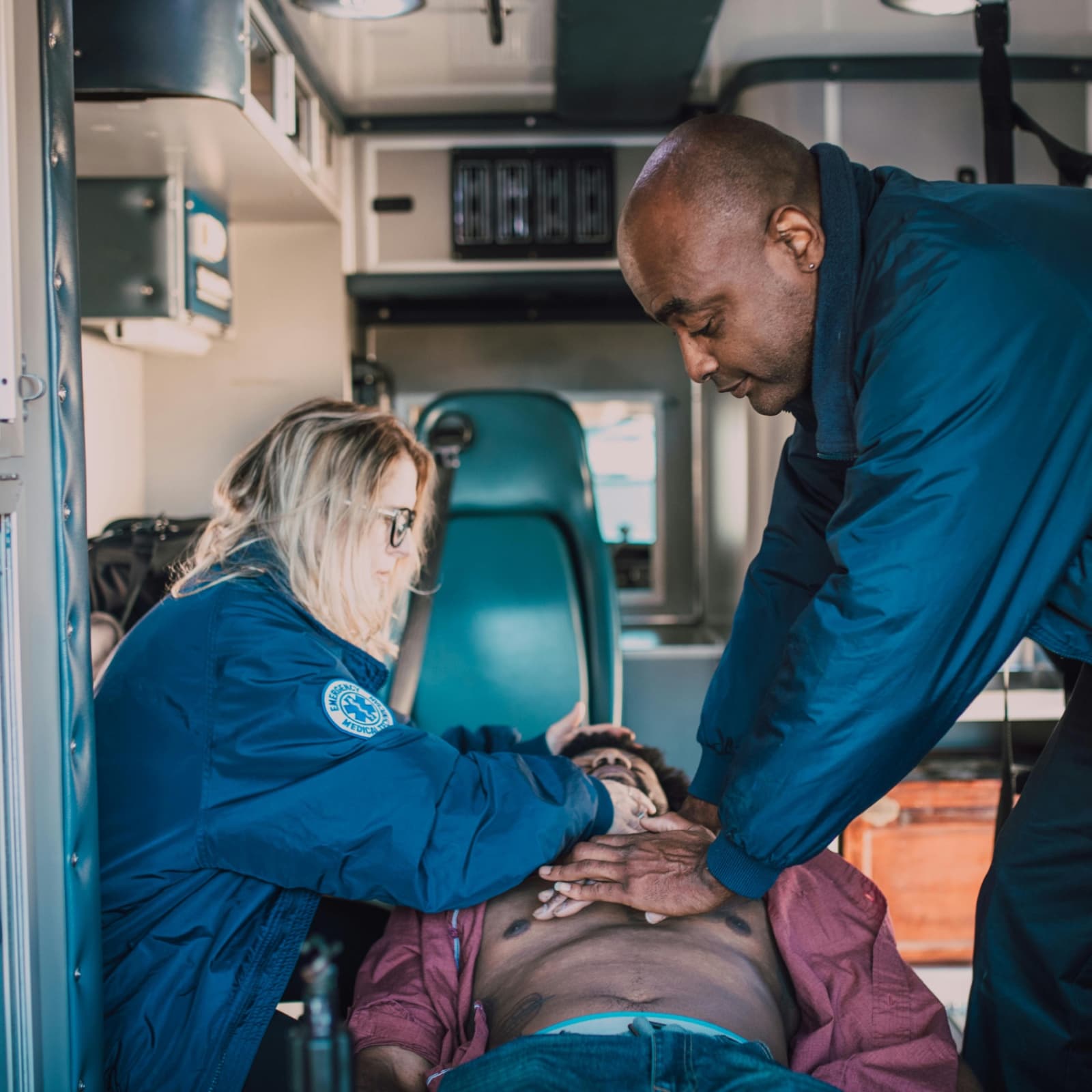 Paramedics performing CPR on a patient inside an ambulance during a BLS training scenario