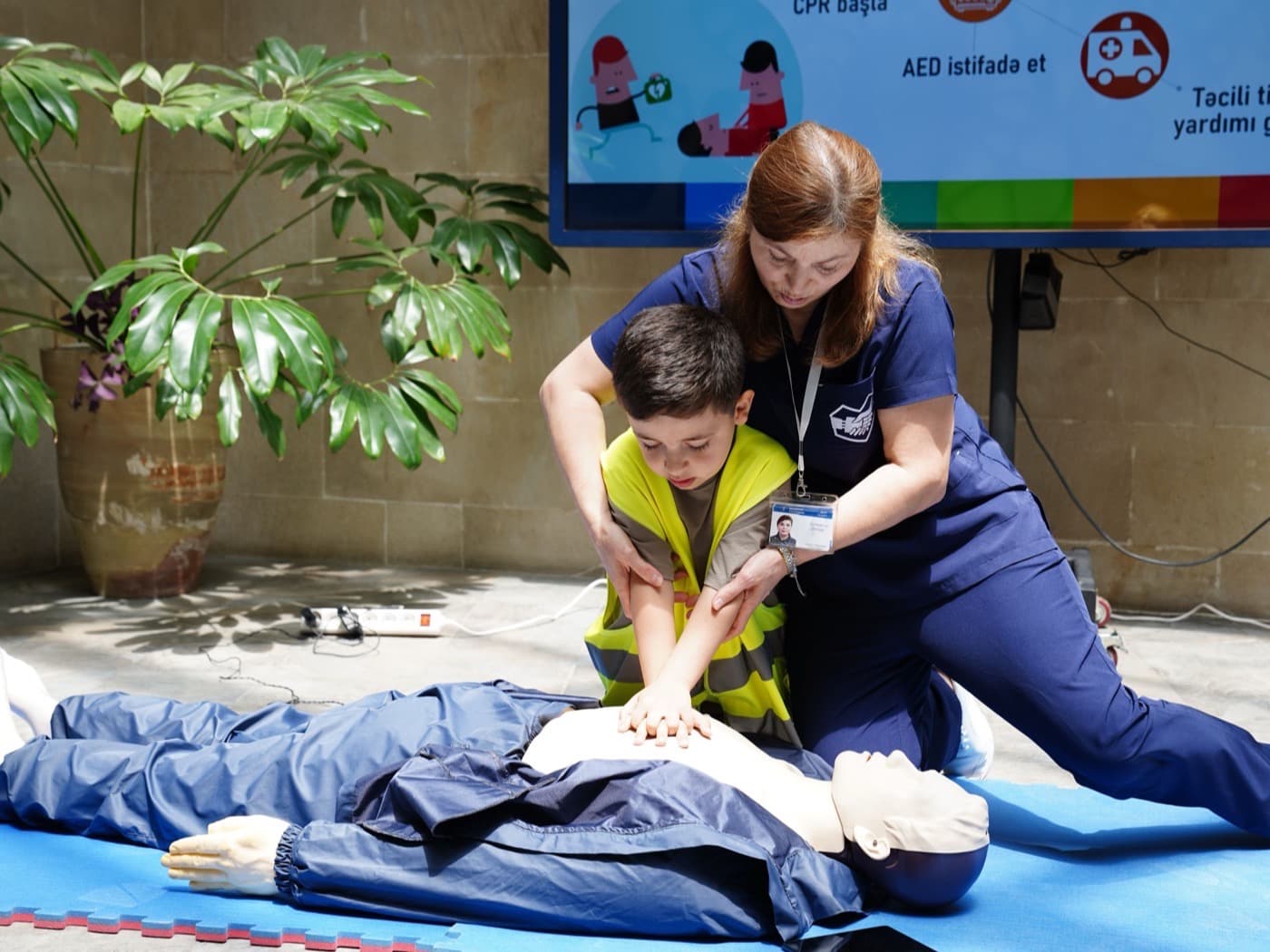 Instructor guiding a student through chest compressions on an adult CPR mannequin